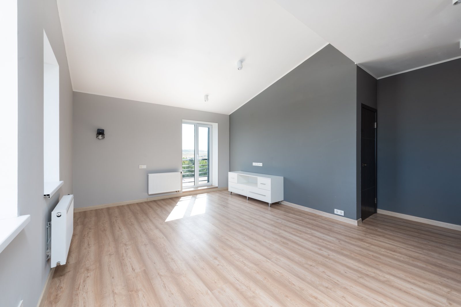 Leerer Raum mit Holzboden und Balkontür